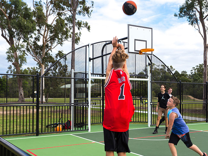 teenagers playing basketball on a multi-use games area